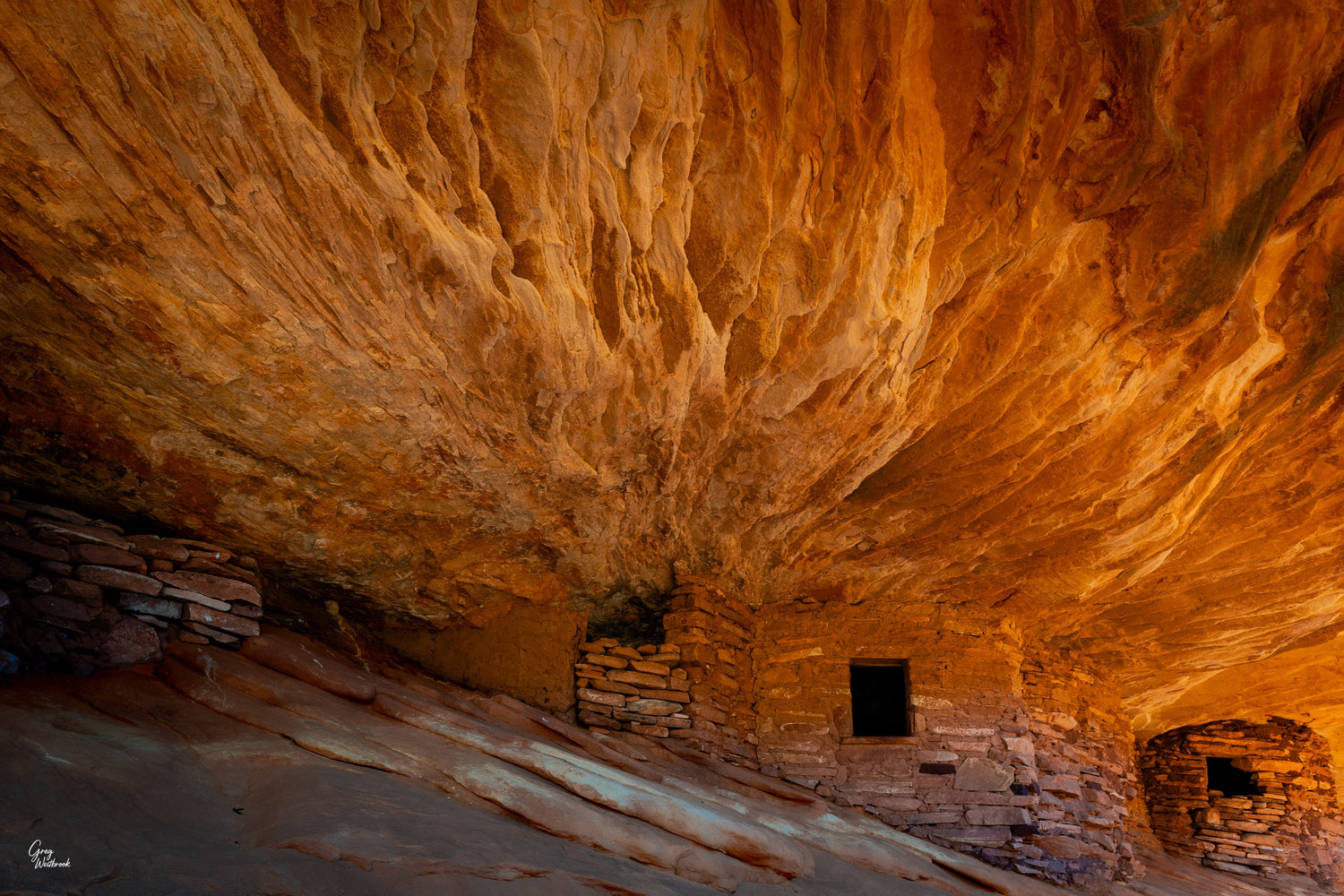 Ancient sandstone cliff dwellings glowing beneath a warm, firelit canyon ceiling fine art photography collection