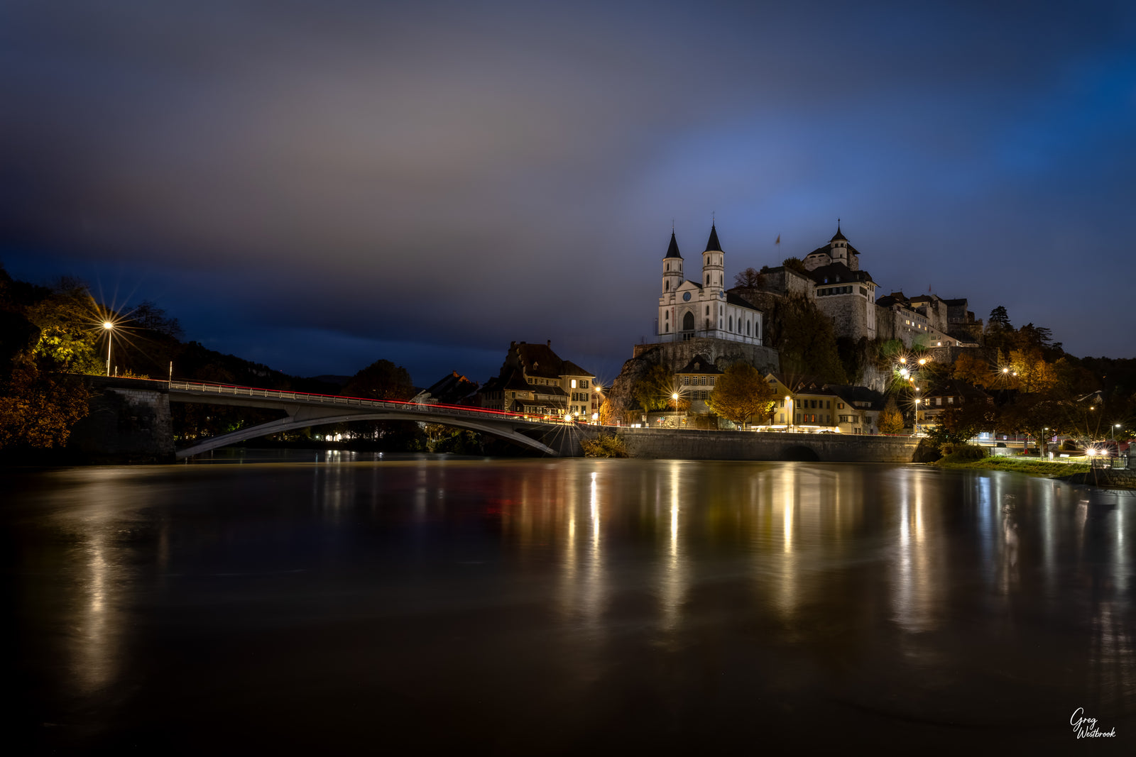 Swiss town of Aarburg at twilight with illuminated fortress reflected in a calm river