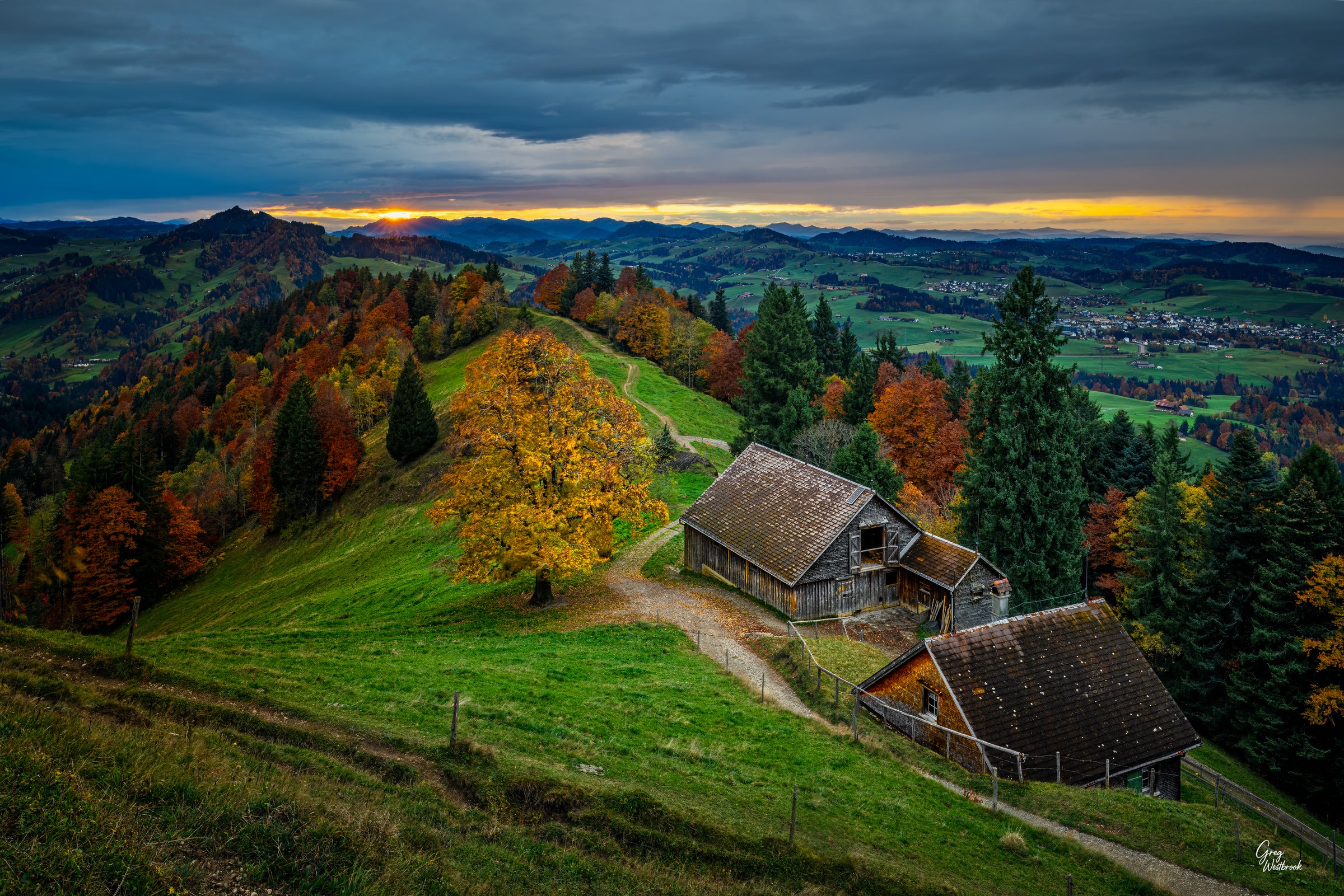 Rolling Swiss countryside glowing at sunset with autumn color and quiet farm buildings