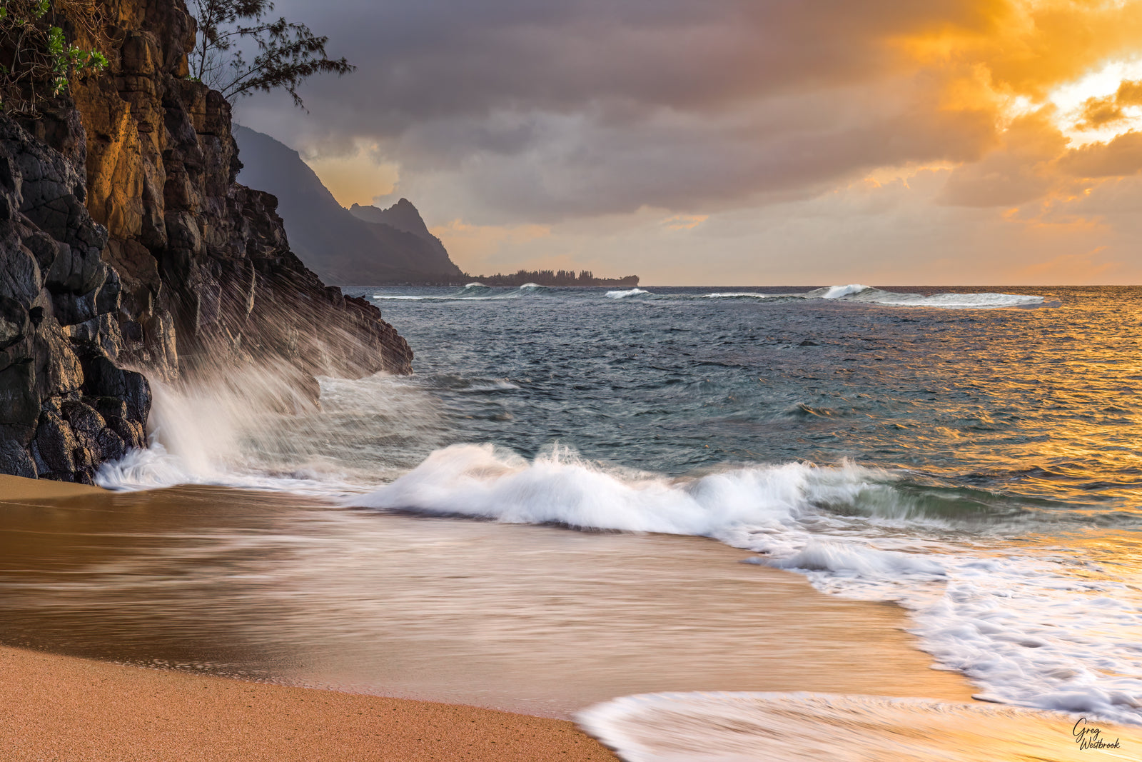 Rocky coastal cliffs glowing in warm light as ocean waves crash along a sandy shore