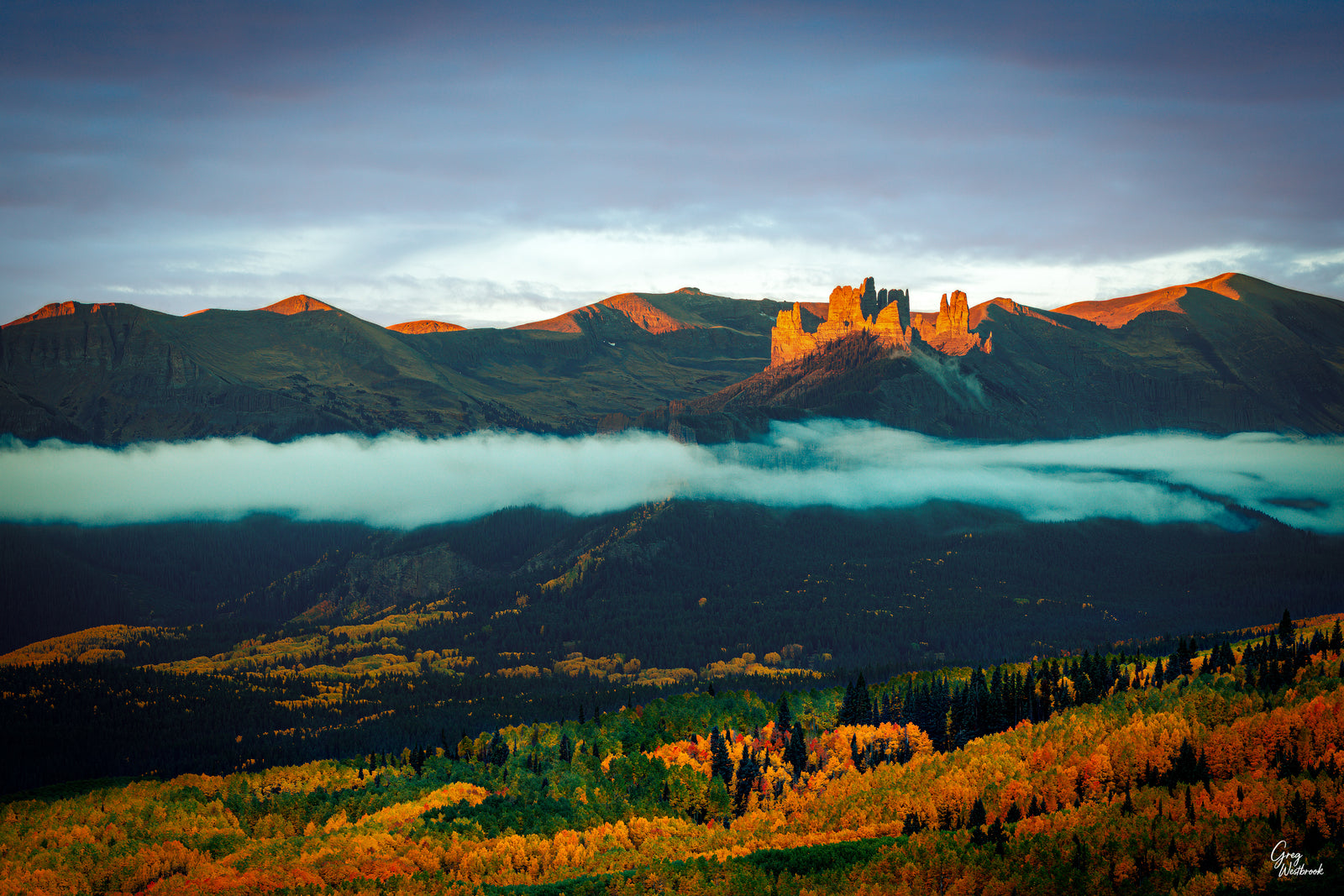 Sunrise lighting the spires of The Castles above autumn aspens and drifting clouds